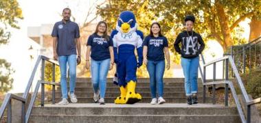 Four students walking down the outdoor steps with Auggie the mascot